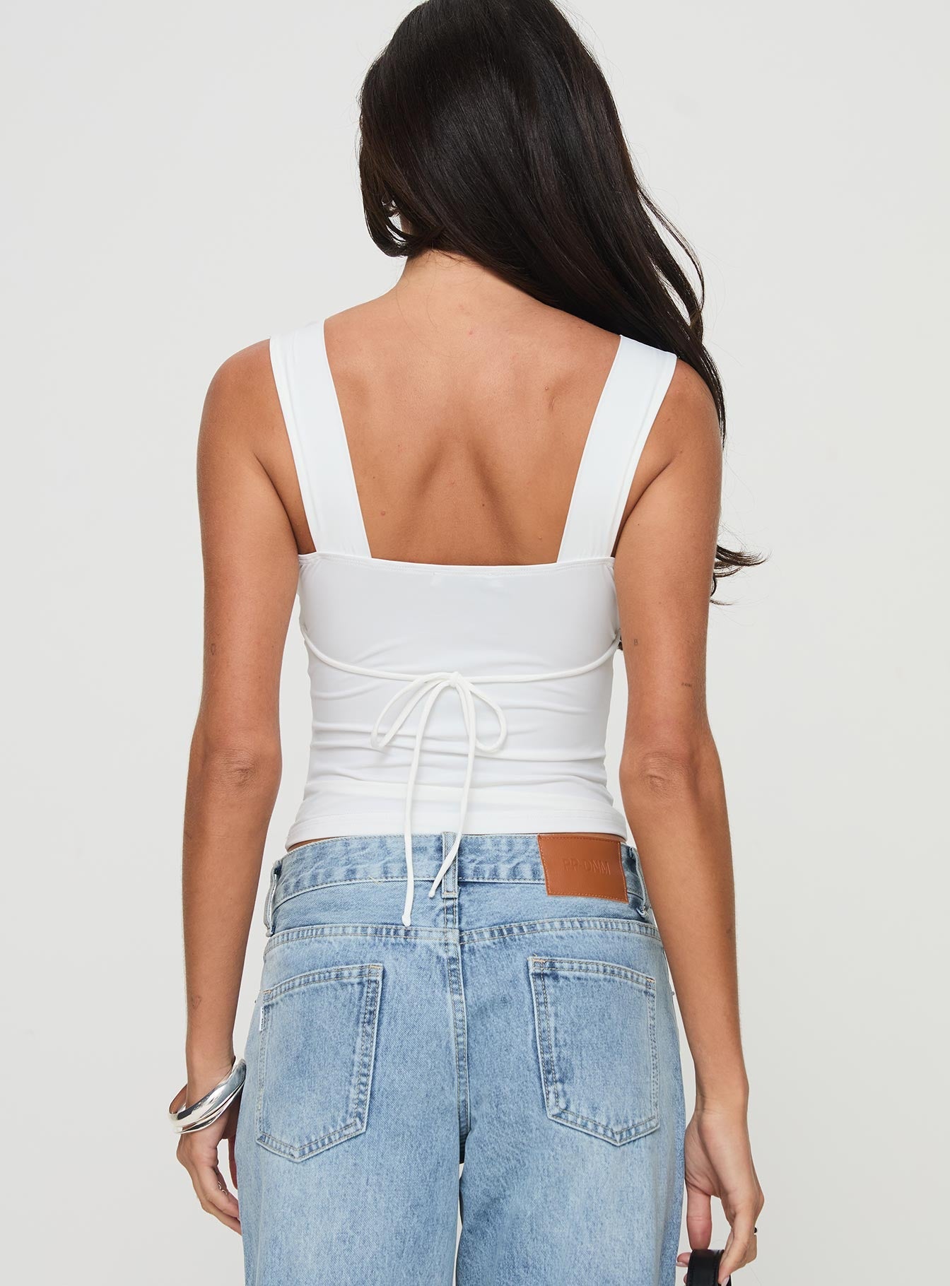back view of model wearing Princess Polly Zyair Top White Sleeveless Plunger 