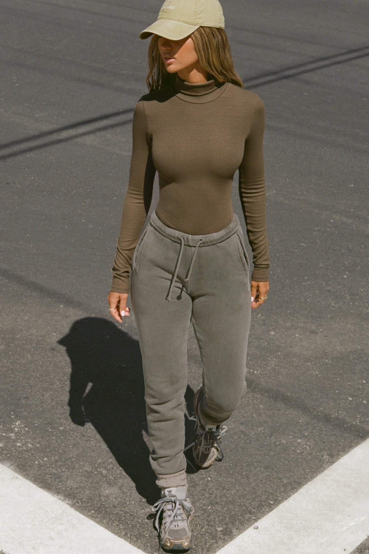 Full body front view of model posing outside in the street in the form-fitting and stretchy woodland rib Classic Turtleneck long sleeve top
