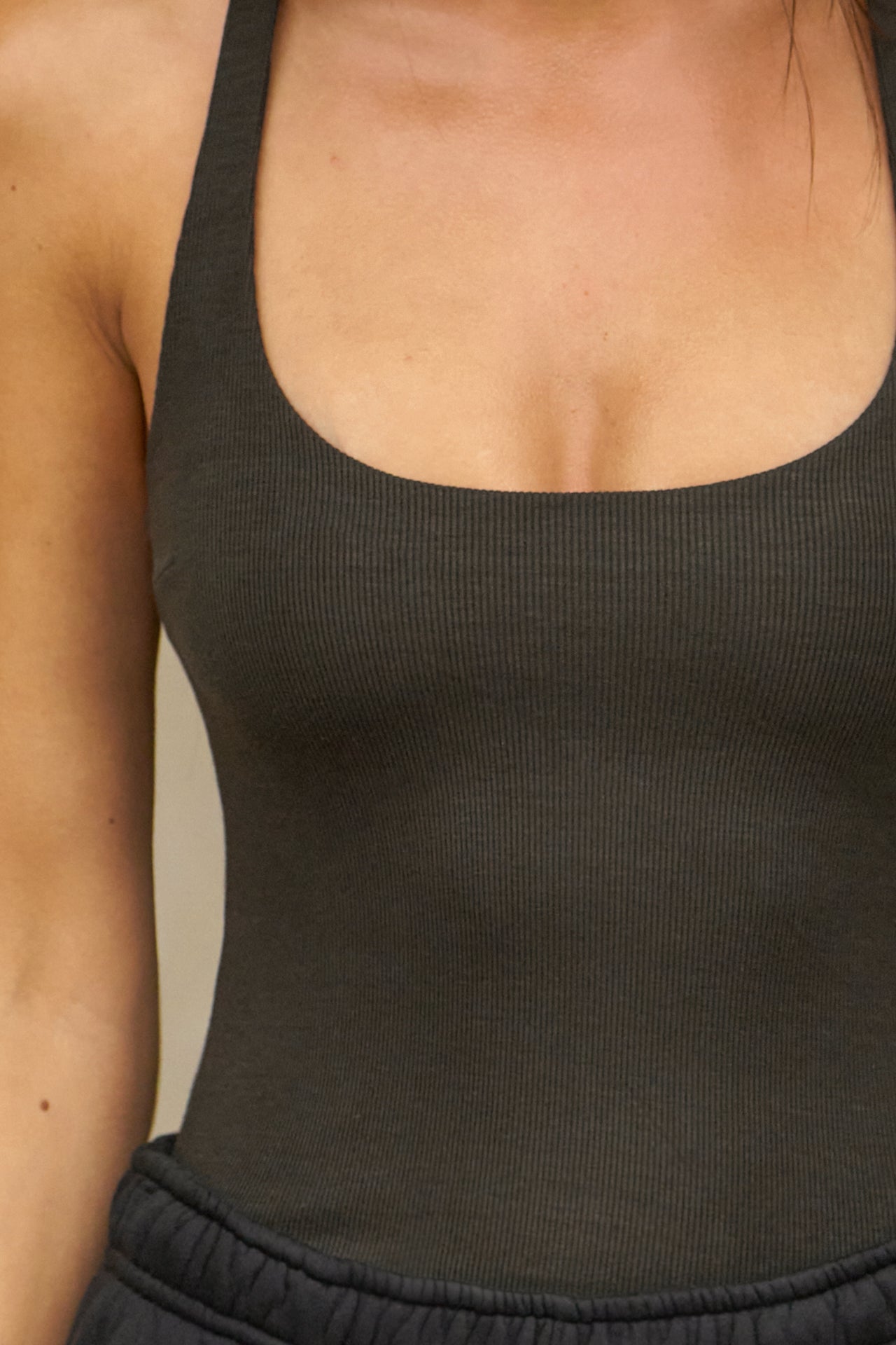Close up detail front view of model posing in the vintage black flexrib Classic Racerback Tank with a scoop neckine and racerback silhouette. 