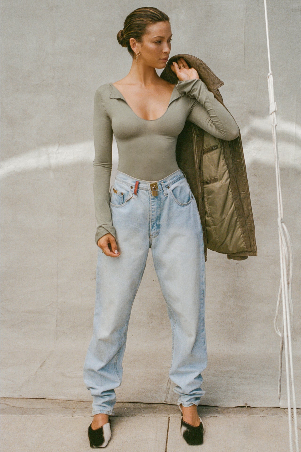 Full body front view of model posing in the fitted sage modal Notched V Neck Long Sleeve top with a deep notched V-neckline, extra long sleeves and small side slits at the hem