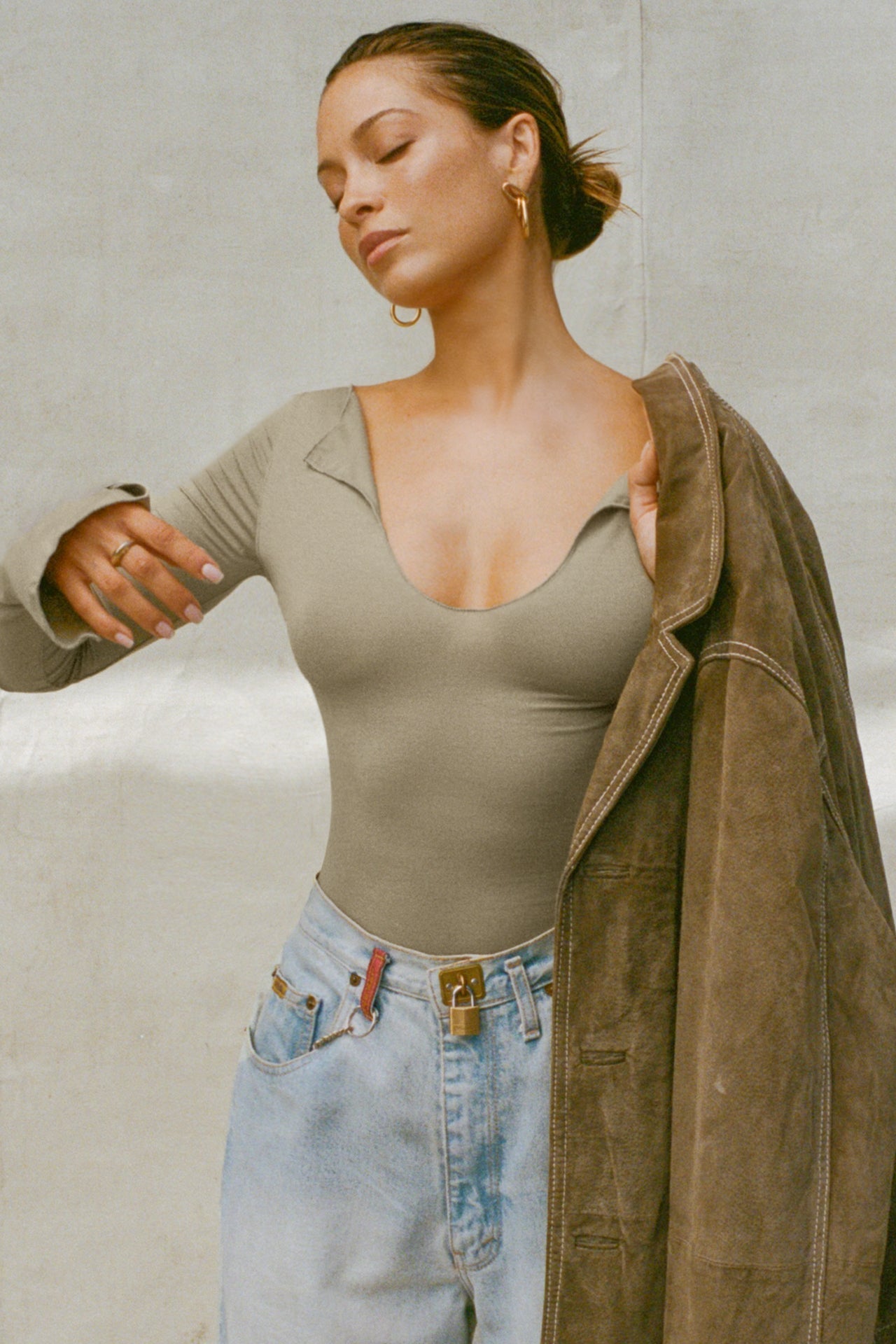Front view of model posing in the fitted sage modal Notched V Neck Long Sleeve top with a deep notched V-neckline, extra long sleeves and small side slits at the hem