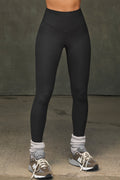 Front view of model from the waist down posing the full length and high-waisted sueded onyx Second Skin Legging with a wide, v-shaped waistband