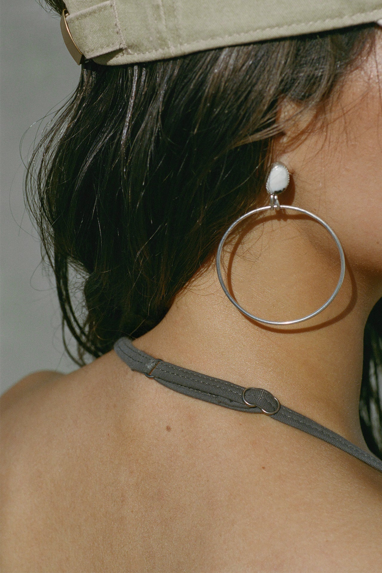 Close up detail back view of model posing in the fitted and smoothing sueded carob Halter Scoop Tank with a scoop neckline, open back and narrow, adjustable neck strap. 