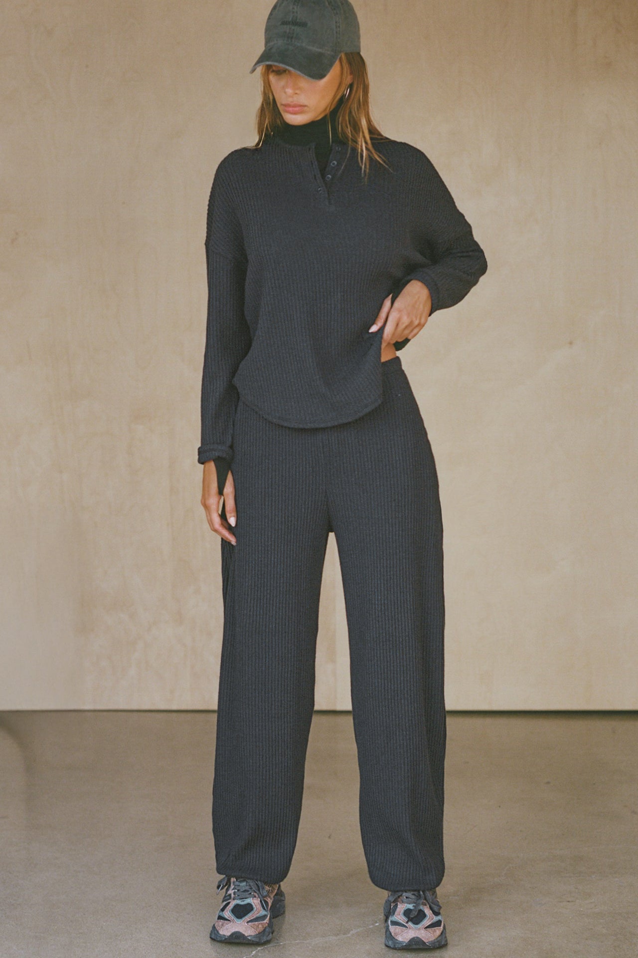 Full body front view of model posing in the relaxed-fit midnight luxe knit Henley Pullover long sleeve top with a buttoned henley neckline and curved hem.
