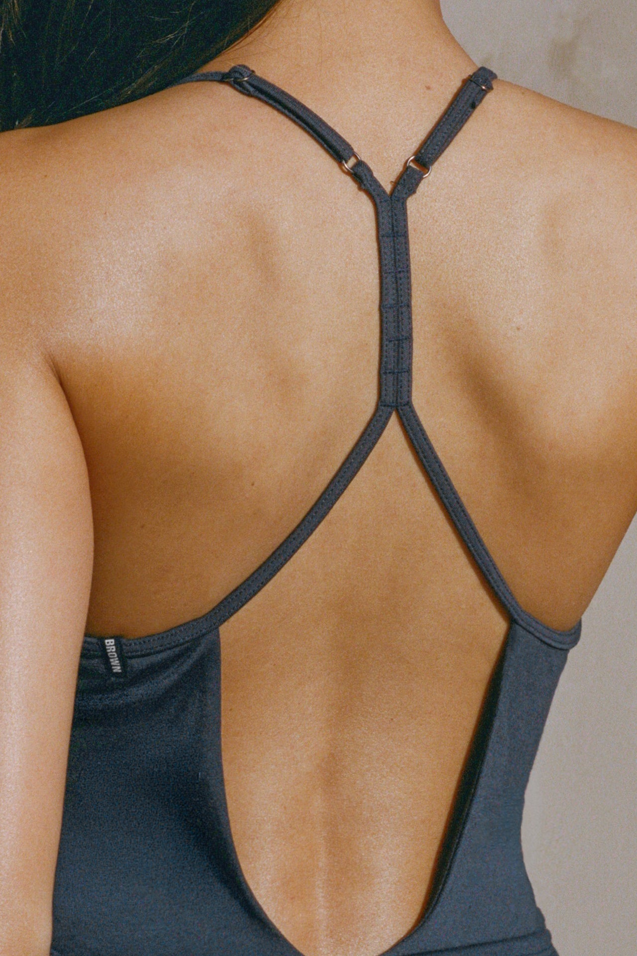 Close up detail back view of model posing in the fitted navy modal Open T-Back Cami with an open t-back design