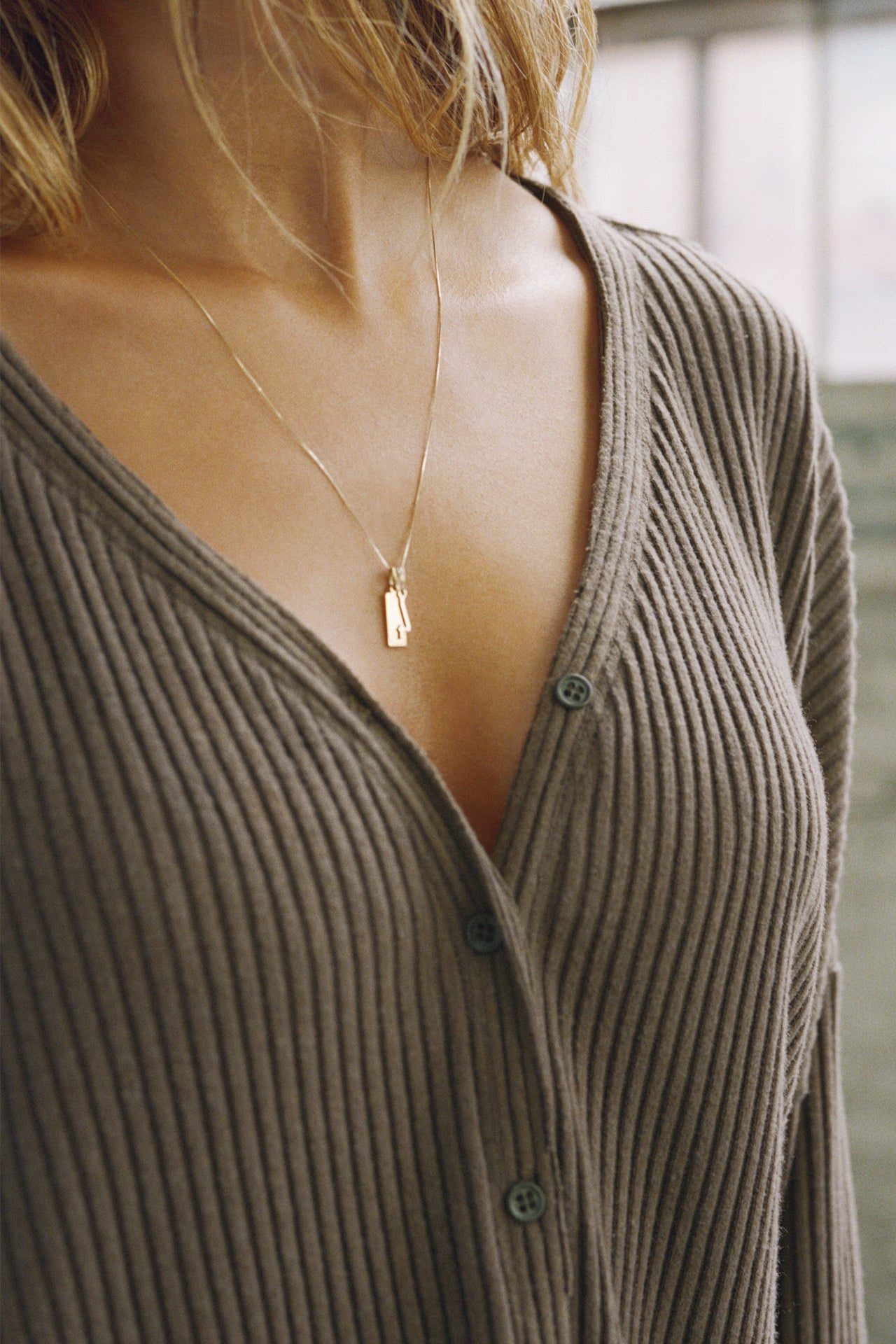 Close up detail front view of model posing in the relaxed-fit, long sleeve army luxe knit Relaxed V-Neck Cardigan with front button closures and a V-neckline.