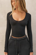 Front view of model posing in the fitted lightweight black modal Scoop Neck Long Sleeve top with a deep scoop neckline and fitted sleeves