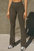 Front view of model from the waist down posing in the full length bootcut sueded carob Second Skin Bootcut Legging with a wide v-shaped waistband and split detail at the leg opening